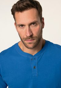 Kungablå långärmad skjorta med rundad halsringning, tvåknappsstängning och en mjuk textur. Enkelt mönster utan ytterligare motiv eller accent.