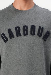 Γκρι φούτερ με κολάρο τύπου crew και ανάγλυφο μπλε navy λογότυπο "BARBOUR" στο στήθος. Μαλακή υφή και χαλαρός σχεδιασμός.