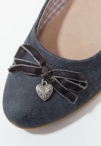 Ballerine en daim bleu foncé avec un nœud en velours sombre et un petit charme argenté en forme de cœur sur l'avant.