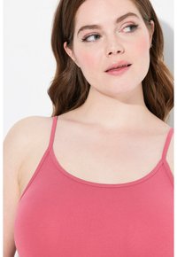 Top rosa con spalline sottili, realizzato in un tessuto liscio e elasticizzato. Presenta un colletto arrotondato e una silhouette aderente.