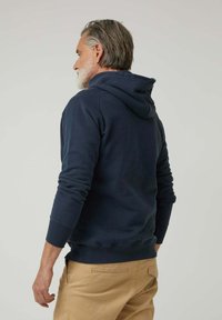 Sudadera con capucha azul marino con un bolsillo tipo canguro y puños acanalados. Presenta un ajuste relajado y capucha con cordón, confeccionada en tela suave.