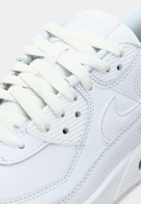 Weiße Leder Sneaker mit strukturierten Seitenpaneelen, flachen Schnürsenkeln und einem sichtbaren Logo. Weiche Minzakzente verleihen dem Gesamtdesign eine besondere Note.