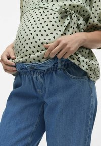 Camicia verde chiaro con motivo a cuori neri, abbinata a jeans in denim blu con cintura elastica per il massimo comfort.