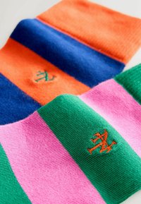 Deux paires de chaussettes rayées avec des logos brodés orange et vert ; une paire orange et marine, l'autre rose et verte.