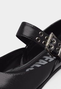 Μαύρο παπούτσι μπαλαρίνα από δέρμα με πατέντα, με ρυθμιζόμενο λουράκι στον αστράγαλο που διαθέτει μεταλλική αγκράφα και οπές, με εμφανές λογότυπο στην εσωτερική σόλα.