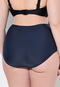 Kraťasy s vysokým pasem v tmavě modré barvě, vyrobené z hladkého, elastického materiálu bez švů a s zakřiveným zadním střihem.