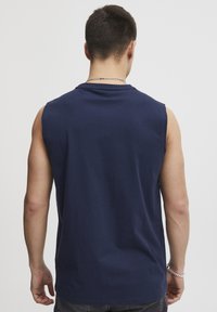 Maglietta senza maniche in cotone di colore blu navy con scollo tondo. Tessuto liscio, stile aderente e cuciture delle spalle visibili. Design semplice, senza motivi o dettagli.