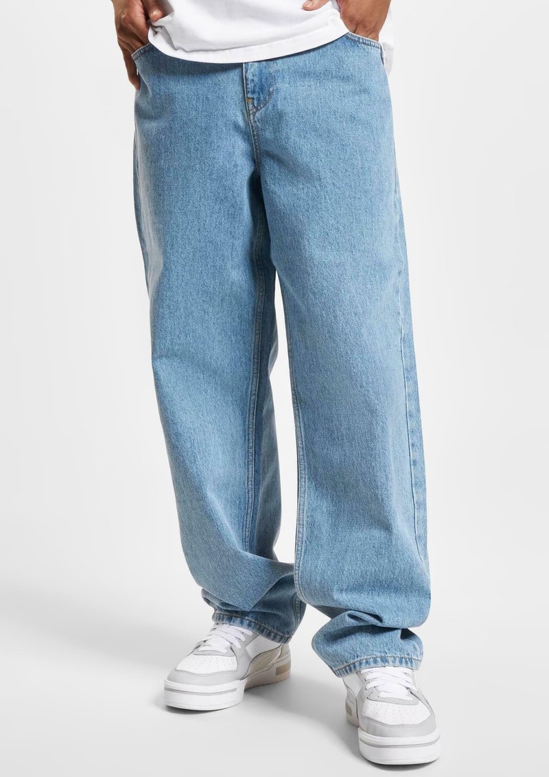 Light blue, wide-leg denim jeans with a raw hem and classic five-pocket design, paired with white sneakers featuring gray accents.