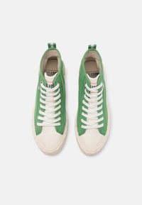 Sneakers high-top verdi con lacci bianchi, in tessuto di tela, suola in gomma e punta crema. Presentano un'etichetta con logo e un'asola sul tallone a righe.