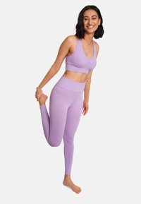 Lavender Sport-BH und Leggings-Set aus dehnbarem Stoff. Der BH hat einen runden Ausschnitt und eine gerippte Textur, die Leggings sind hoch geschnitten und figurbetont.
