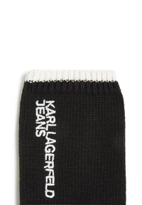 Black knitted sock with a white ribbed cuff. Features embroidered "KARL LAGERFELD JEANS" logo on the side. Soft texture, medium height.