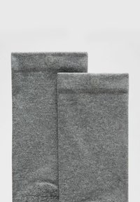 Harmaat puuvillasekoitesukat, joissa on teksturoitu kuvio ja ribbausreuna, varustettuna pienellä logolla sukan yläosassa.