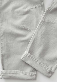 Pantaloni in denim grigio con una texture liscia, caratterizzati da orli arrotolati e tasche laterali. Il design semplice e le linee pulite enfatizzano uno stile moderno.