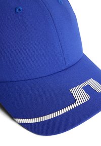 Blå basebollkeps i texturerad tyg med ett randigt vitt logoprydnad framtill och kontrasterande sömnadsdetaljer.