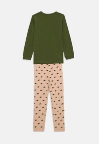 Long-sleeve green cotton top paired with pink pajama pants featuring a turtle pattern in dark green. Soft texture, casual design.