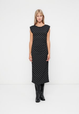 Black midi dress with white polka dots, featuring cap sleeves and a soft texture. Worn with knee-high black boots.