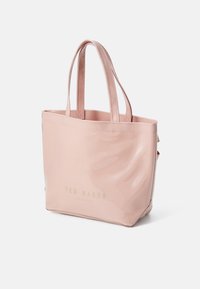 Sac fourre-tout en cuir verni rose avec deux poignées, arborant un logo doré portant la mention "TED BAKER LONDON" sur le devant. Surface lisse sans motifs.