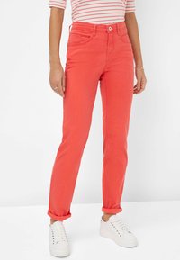 Rote Denim-Jeans mit schmaler Passform und aufgerolltem Saum. Verfügt über fünf Taschen, einen Knopfverschluss und eine glatte Textur. Kombiniert mit weißen Sneakers.