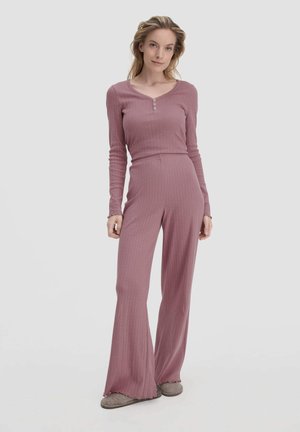 Langärmliger, gerippter Jumpsuit in staubrosa mit Henley-Ausschnitt und weit ausgestellten Beinen, aus weichem Material gefertigt. Mit Knopf-Akzenten.