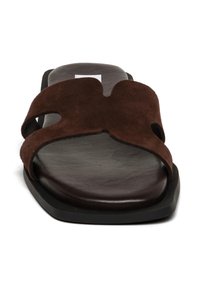 Bruine leren slidesandal met twee uitsnijdingen en een platte zwarte zool. Soepele textuur met een minimalistisch ontwerp.