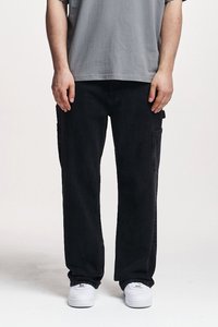 Pantalones cargo de mezclilla negra con bolsillos laterales, diseño de pierna recta y una tela ligeramente texturizada. Combinados con zapatillas blancas y una camiseta gris.