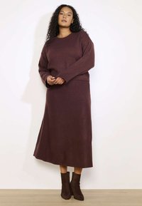 Burgundi värvi kudumissviiter ja sobiv midi seelik. Pehme tekstuur, mugav lõige ja pikad varrukad. Kanda pruunide pahkluusaabastega heledal puidust põrandal.