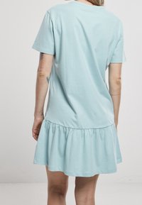 Jasnoniebieska bawełniana sukienka-t-shirt z krótkimi rękawami i rozszerzanym, falbaniastym dołem. Gładka tekstura, prosty design i nieozdobiony tył.