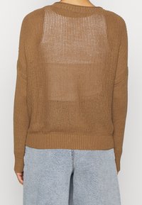 Maglione marrone lavorato a maglia con una vestibilità ampia, caratterizzato da un motivo testurizzato e polsini e orlo a coste. La parte posteriore presenta una sezione semi-trasparente.