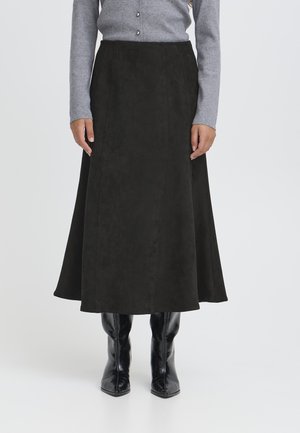 Gonna midi in camoscio nero con una silhouette svasata, dotata di dettagli in cuciture verticali. Indossata con un top grigio a maniche lunghe e stivaletti neri.