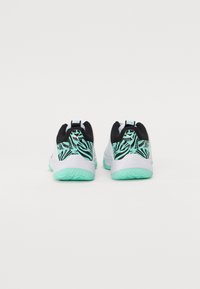 Chaussures de sport avec une tige en mesh noire, un talon turquoise à motifs, une semelle intermédiaire blanche et une semelle légère verte présentant des grips texturés.