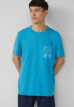 Korte mouwen t-shirt in helder teal, met een gestructureerde zak met een subtiel patroon. Zachte stof met een ontspannen pasvorm.