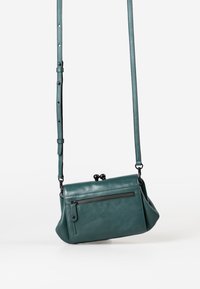 Borsa a tracolla in pelle teal con una forma strutturata. Presenta una tasca con zip, una tracolla regolabile e due dettagli a chiusura rotonda.
