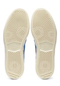 Niebieskie trampki z teksturowaną białą gumową podeszwą z wzorem siatki. Z boku widoczna jest logo i czerwone akcenty.