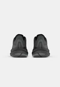 Schwarze Sportschuhe mit einer strukturierten Oberseite, abgerundetem Absatz und gemustertem Sohlenprofil, mit einem Logo auf der Rückseite und geschwungenen Designelementen.