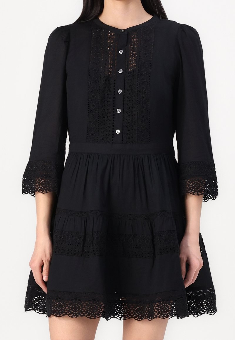 Black knee-length dress with long sleeves, featuring lace accents, button front, and a tiered skirt. Textured with intricate lace detailing.