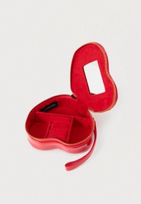 Κόκκινη θήκη κοσμημάτων σε σχήμα καρδιάς με γυαλιστερή εξωτερική επιφάνεια, κλείσιμο με φερμουάρ και μαλακό εσωτερικό. Περιέχει διαχωρισμένα τμήματα και καθρέφτη.