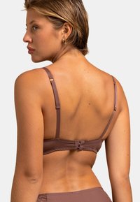 Soutien-gorge marron avec des bretelles réglables et une fermeture à crochets. Tissu lisse avec une légère brillance et des accents en dentelle le long de la bande.