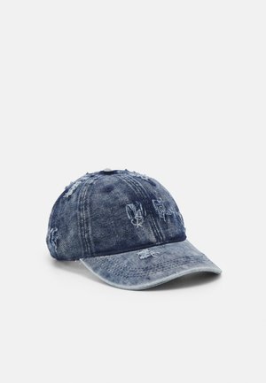 Gorra de béisbol de mezclilla azul desgastada con áreas desteñidas y pequeños desgarros en la corona y la visera, mostrada sobre un fondo liso.