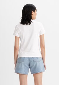Vit bomull t-shirt med korta ärmar, något figurnära design. Bärs med ljusblå denimshorts med bakfickor och sydda detaljer.