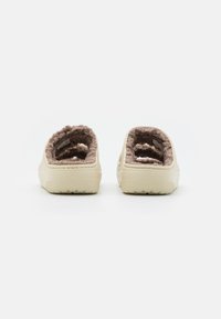 Krémové slip-on topánky s mäkkým hnedým vnútorným podšívkou, vyrobené z gumovitého materiálu s textúrovanou podrážkou pre lepšiu priľnavosť.