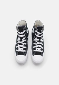 Sneakers alte in tela nera con lacci bianchi, punta in gomma bianca e patch con logo sui lati. Parte superiore testurizzata con cuciture a contrasto.