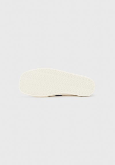 Kingade tekstuuriga laineline disain off-white värvuses, millel on veidi tõstetud konts ja tumehämaruse aktsent kontsa piirkonnas.