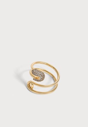 Gyldent åbent spiralring med den ene ende prydet med små, klare krystaller i en slangelignende form på en lysegrå baggrund.