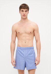 Blå og hvite stripete badebukser med elastisk midje, med klassisk snitt og lett stoff.
