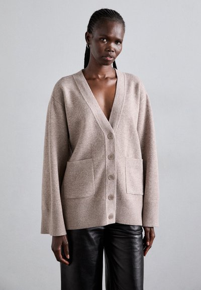 Cardigan beige avec un décolleté en V profond, fermeture à cinq boutons, deux poches avant et des poignets côtelés, fabriqué en tissu texturé doux.