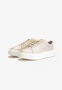 Beige nahkakengät valkoisella kumipohjalla, pyöreällä kärjellä ja tasaisilla nauhoilla. Korkealaatuinen sileä pinta, jossa on huomaamatonta ommelta ja ilman näkyviä logoja.