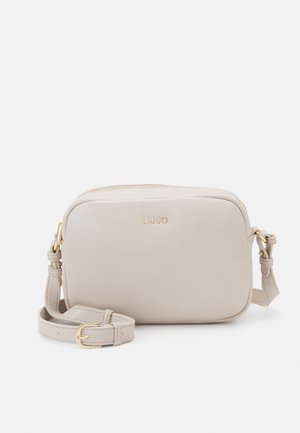 Petit sac bandoulière en cuir beige avec bandoulière réglable et boucle dorée, avec un logo doré subtil sur le devant.