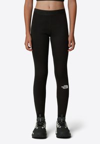 Svarta leggings med en texturerad midjeband som har "THE NORTH FACE"-logotypen. Tillverkade av stretchigt material, designade för komfort och rörlighet.