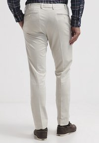 Ljusbeiga chinos med rak passform, som har två bakfickor och subtila sömnadsdetaljer. Mjukt tyg med en slät yta.