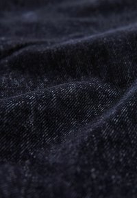 Tummansininen kangas, jolla on pehmeä koostumus, hienovarainen ribbikuvio ja hieman kiiltävä pinta, näkyy taitteista ja rypyistä.